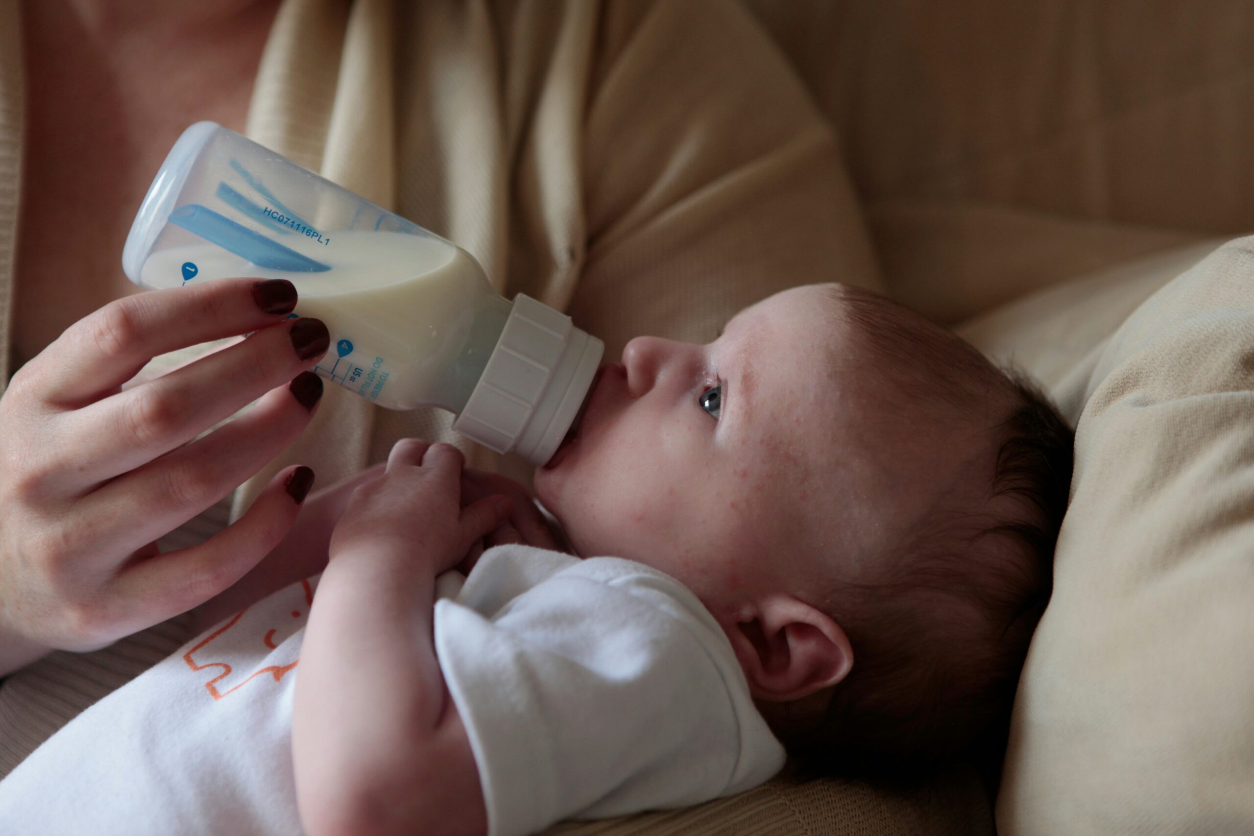 Mamma che usa il tiralatte accanto al neonato nel lettino
